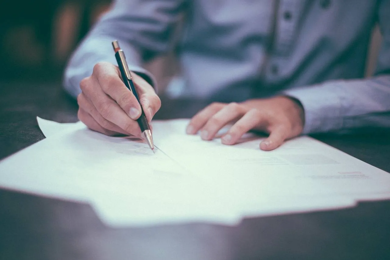A person signing a form with a pen
