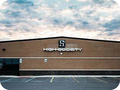 A brick High Society store with its H logo sign at dusk