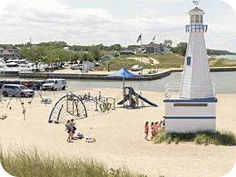 A sandy beach with a playground and a small white lighthouse