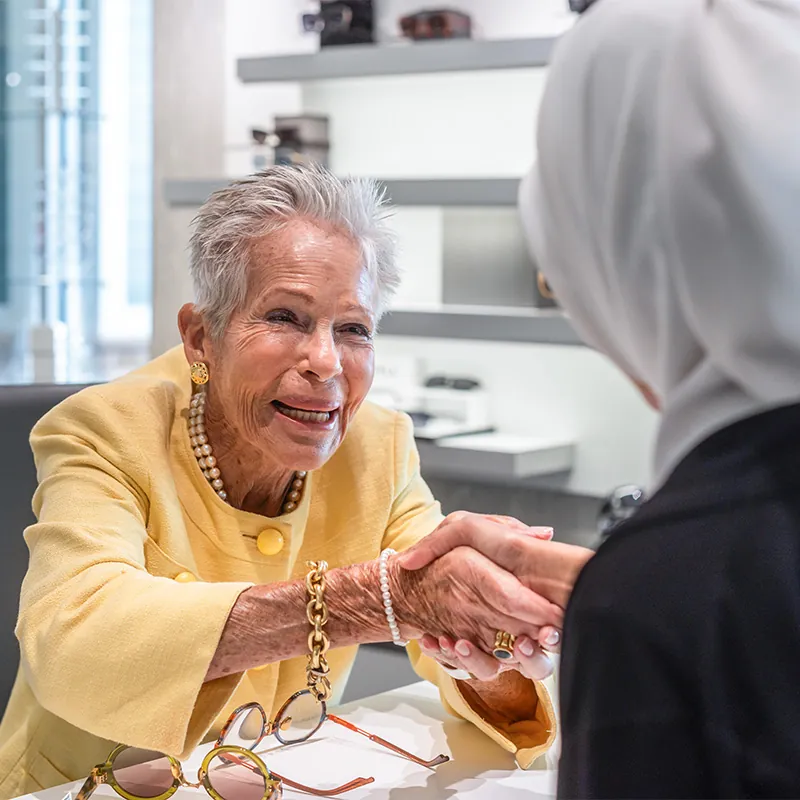 Elderly woman smiling and shaking hands with professional