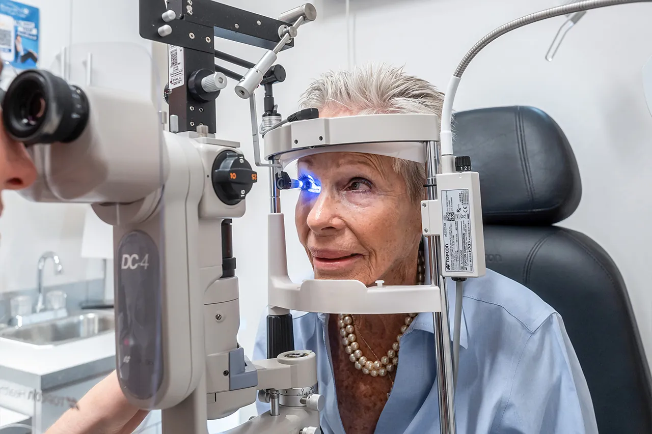 Older woman receiving eye exam with slit lamp biomicroscope