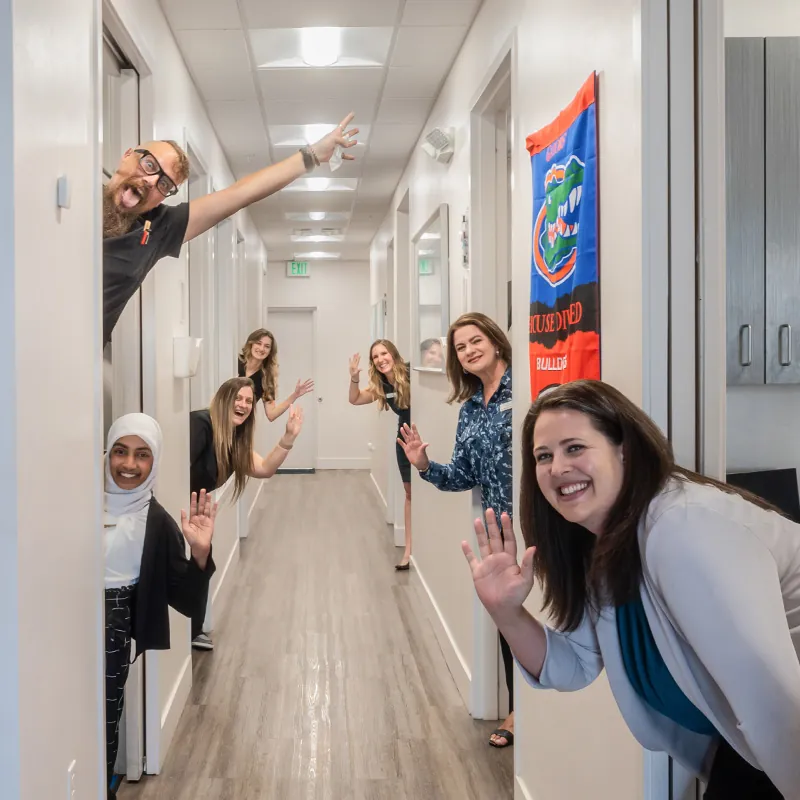 Friendly clinic staff smiling and waving in a hallway