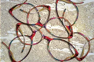 Several red eyeglass frames scattered on a beige surface