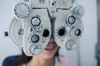 Woman undergoing eye exam with phoropter vision testing device