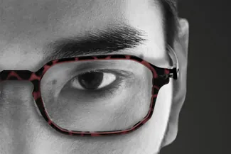 Black and white image of man wearing red eyeglass frames
