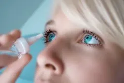Woman applying eye drops to treat eye discomfort or dryness